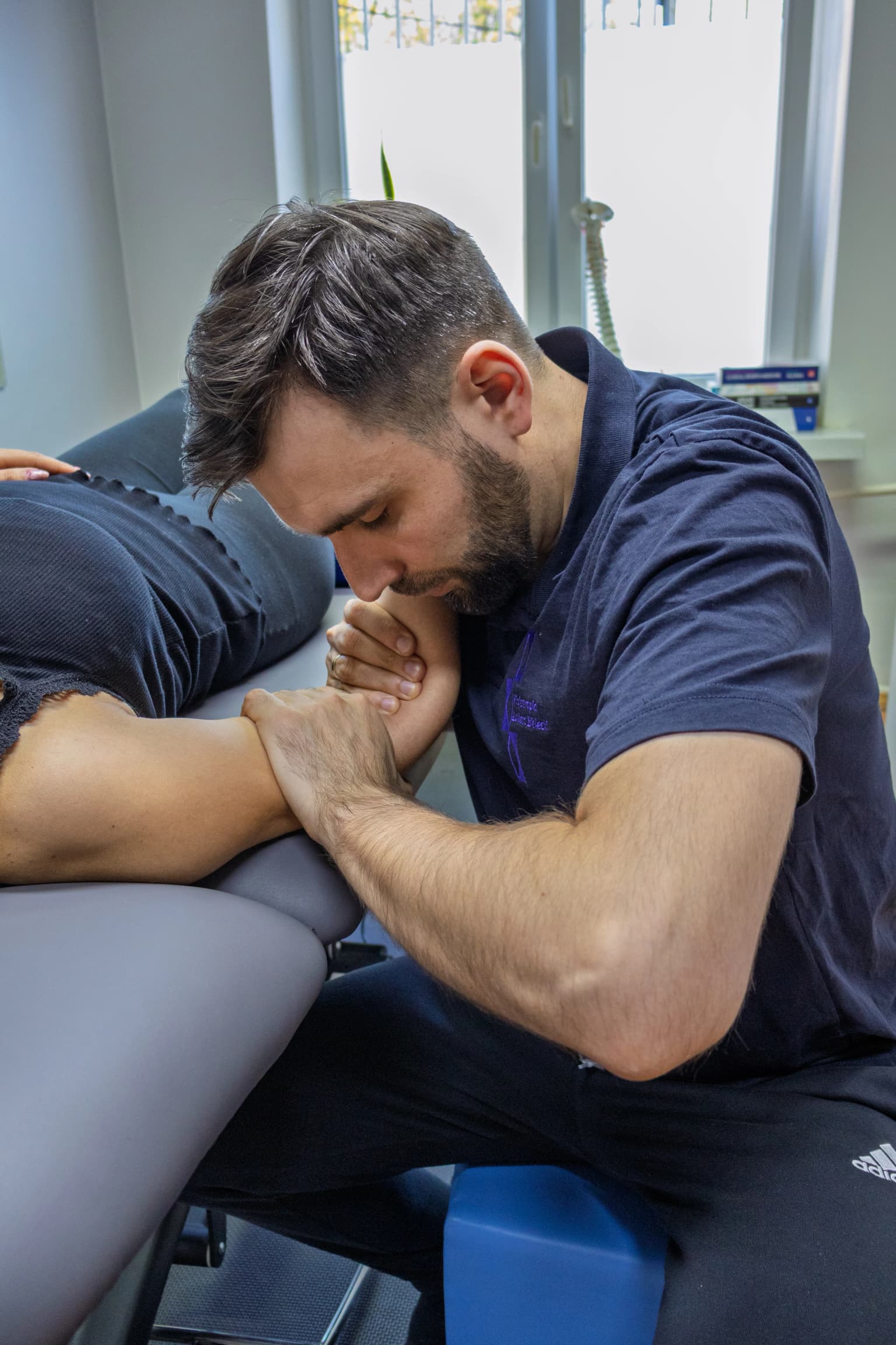 Fizjoterapeuta podczas terapii ręki pacjenta w warunkach domowych