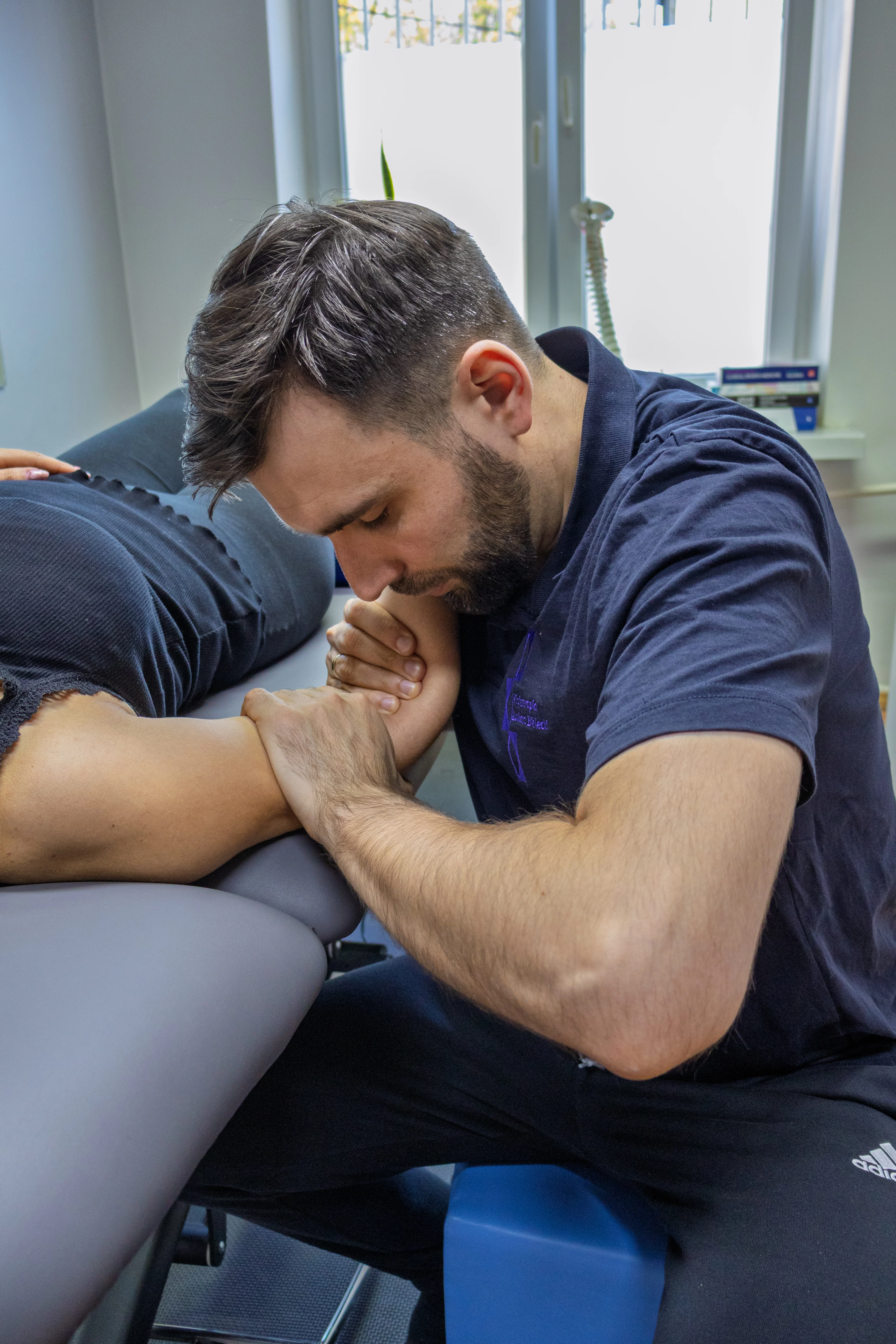 Fizjoterapeuta podczas terapii ręki pacjenta w warunkach domowych